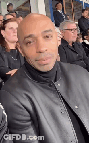 Man In Black Leather Jacket Sitting In Crowd GIF