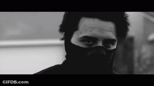 Man In Black Mask Looks At Camera GIF