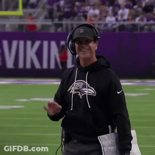 Man In Black Ravens Sweatshirt And Headphones Walking On Football Field GIF