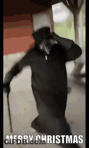 Man In Black Robe And Top Hat Holding Cane Saying Merry Christmas GIF