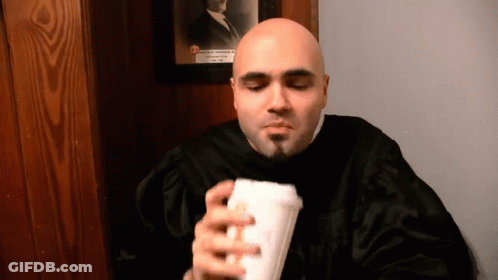 Man In Black Robe Holding Cup In Front Of Portrait GIF