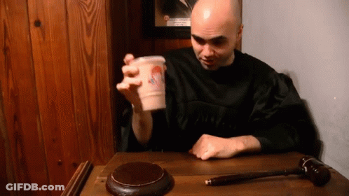 Man In Black Robe Sitting With Cup GIF