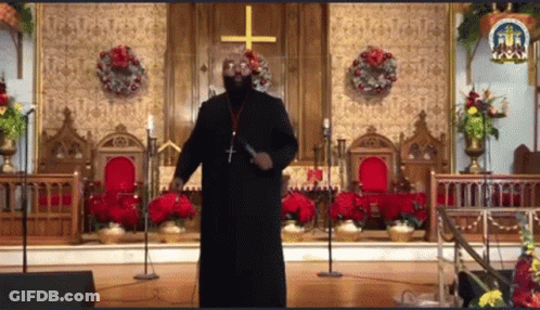 Man In Black Robe Standing In Front Of Church With Cross GIF