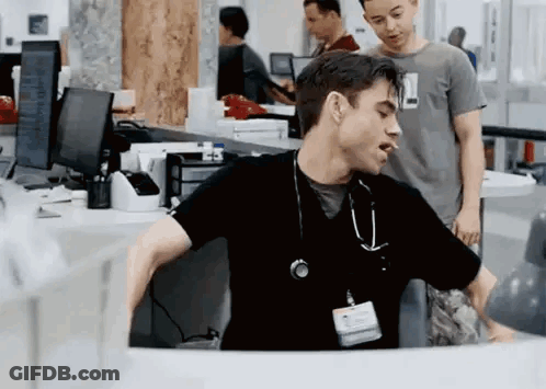 Man In Black Scrub Top With Stethoscope Sitting At Desk GIF