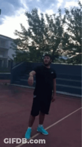 Man In Black Shirt And Blue Shorts On Tennis Court GIF