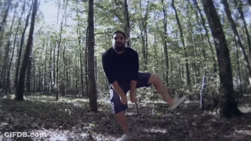 Man In Black Shirt And Blue Shorts Standing In Forest GIF