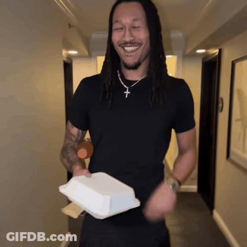 Man In Black Shirt And Cross Necklace Holding Container GIF