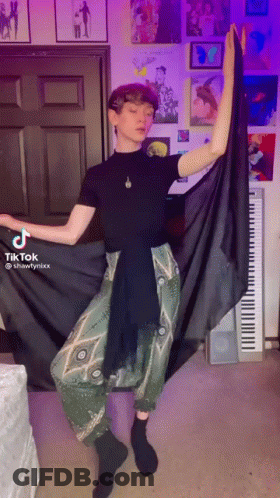 Man In Black Shirt And Green Pants Standing At Piano GIF