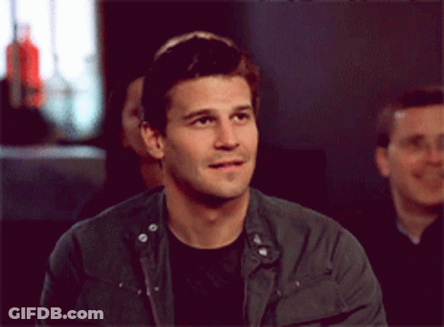 Man In Black Shirt And Grey Jacket Looking At Camera GIF