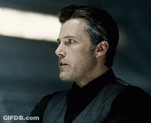 Man In Black Shirt And Grey Vest Looking To Side GIF