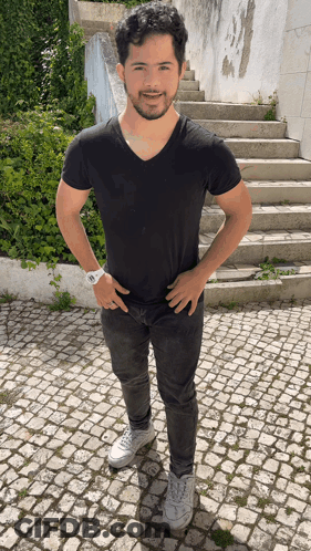 Man In Black Shirt And Jeans Hands On Hips By Stairs GIF