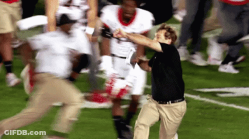 Man In Black Shirt And Khaki Pants Running On Football Field GIF
