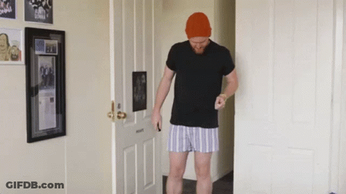 Man In Black Shirt And Striped Shorts In Hallway GIF