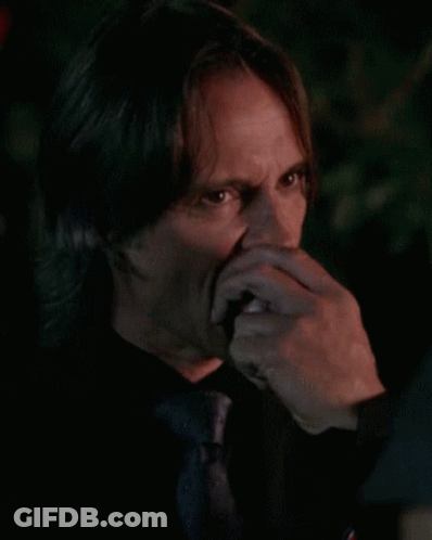 Man In Black Shirt And Tie Biting Food GIF