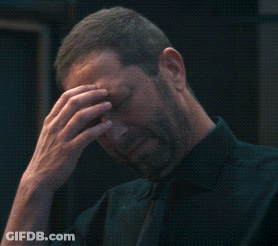 Man In Black Shirt And Tie Holding Head GIF