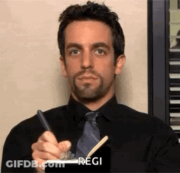 Man In Black Shirt And Tie Holding Pen Notepad GIF