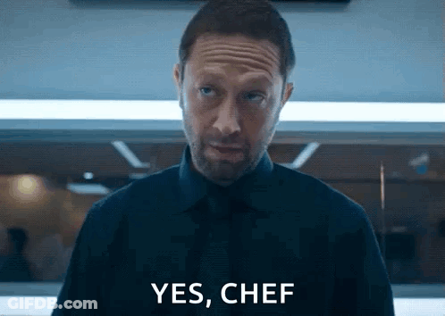 Man In Black Shirt And Tie Saying Yes Chef GIF