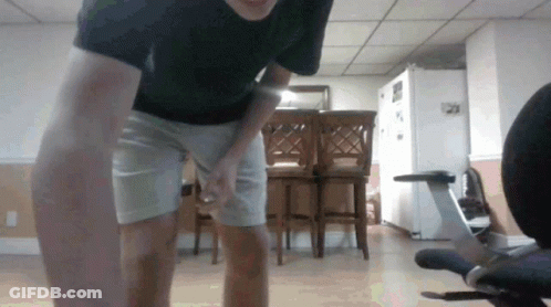 Man In Black Shirt And White Shorts Standing Before Chair GIF
