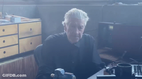 Man In Black Shirt At Desk With Cup GIF