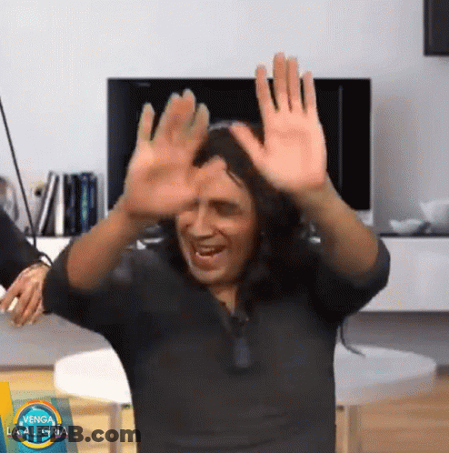 Man In Black Shirt Dancing In Front Of Venga La Alegria Sign GIF