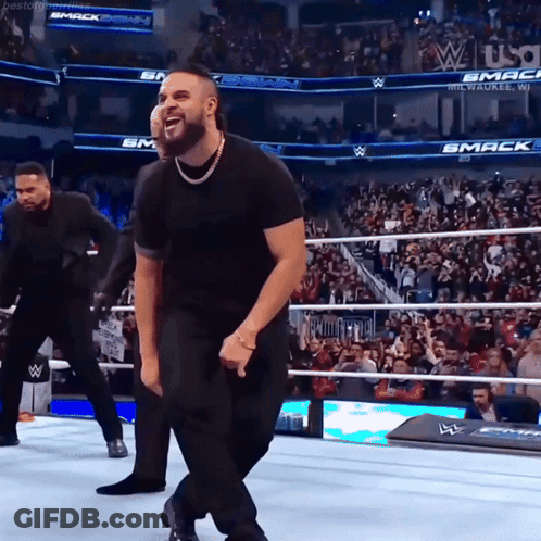 Man In Black Shirt Dancing In Wrestling Ring With Smack Sign GIF
