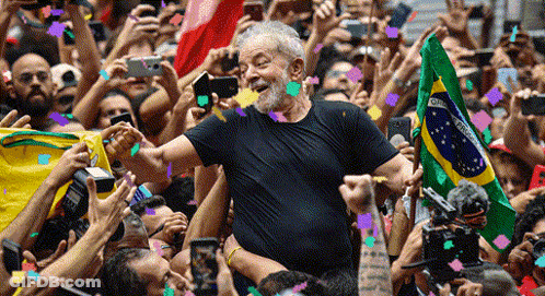 Man In Black Shirt Holding Brazilian Flag In Front Of Crowd GIF