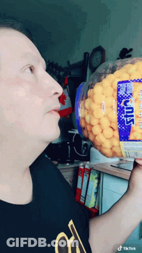 Man In Black Shirt Holding Cheese Puffs GIF