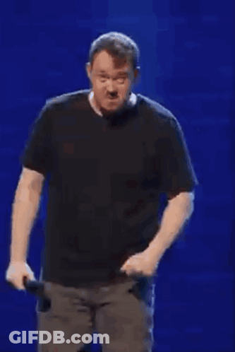 Man In Black Shirt Holding Microphone In Front Of Blue Wall GIF