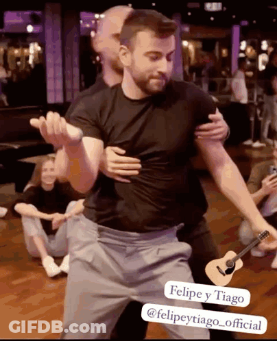 Man In Black Shirt Hugging Another Man With Guitar GIF
