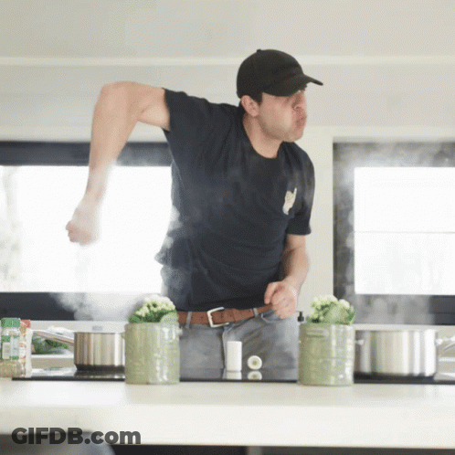 Man In Black Shirt In Kitchen With Pots GIF