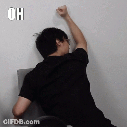 Man In Black Shirt Leaning Against Wall With Fist In Air Saying Oh GIF