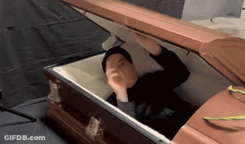 Man In Black Shirt Lying In Open Coffin GIF