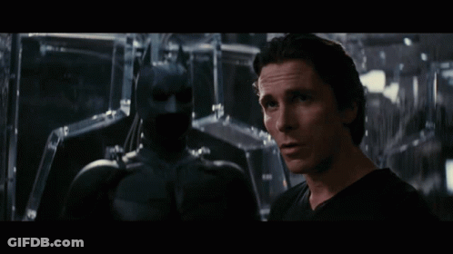 Man In Black Shirt Next To Batman Statue GIF