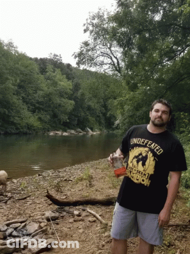 Man In Black Shirt Saying Undefeated Holds Drink GIF