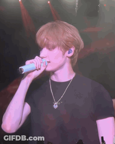 Man In Black Shirt Singing Into Microphone On Stage GIF