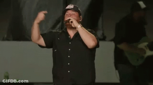 Man In Black Shirt Singing Into Microphone With Eagles Hat GIF