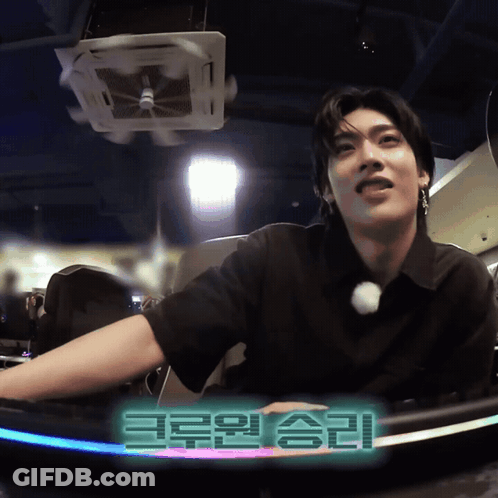 Man In Black Shirt Sitting In Front Of Korean Sign GIF