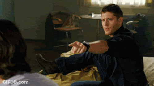 Man In Black Shirt Sitting On Bed Pointing GIF