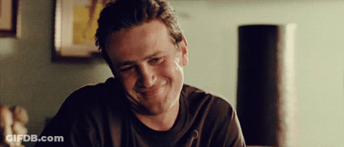 Man In Black Shirt Smiling In Front Of Lamp GIF