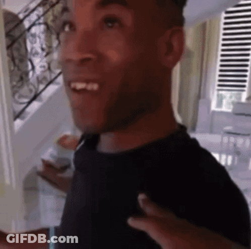 Man In Black Shirt Smiling In Front Of Stairs GIF