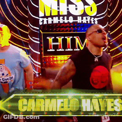Man In Black Shirt Standing Before Carmelo Hayes Sign GIF