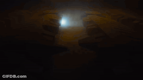 Man In Black Shirt Standing In Front Of Circle In Dark GIF