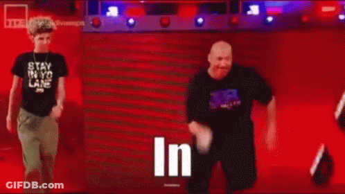 Man In Black Shirt Standing In Front Of Crowd Saying In GIF