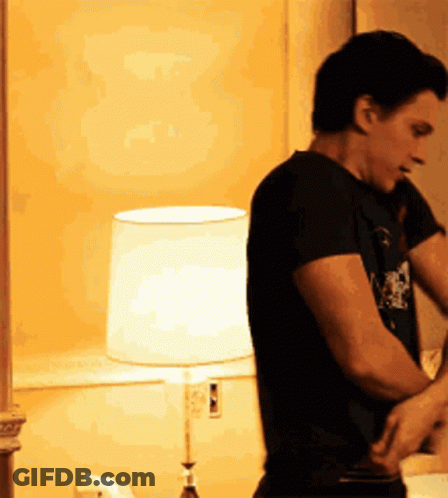 Man In Black Shirt Standing In Front Of Lamp GIF