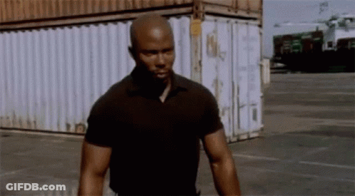 Man In Black Shirt Standing In Front Of Shipping Container GIF