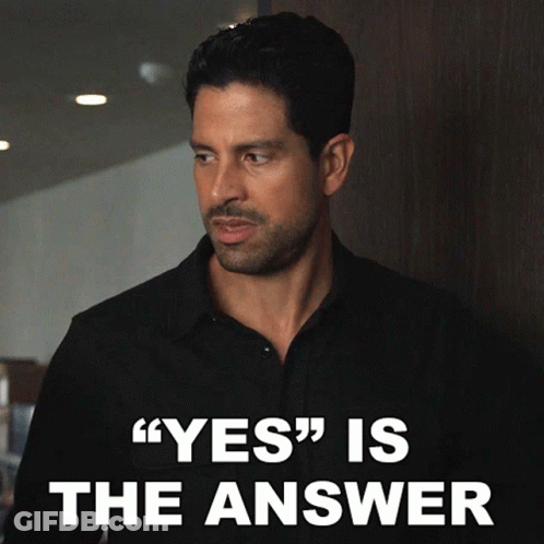 Man In Black Shirt Standing In Front Of Yes Is The Answer Sign GIF