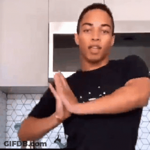 Man In Black Shirt Standing In Kitchen With Hands Folded In Prayer GIF