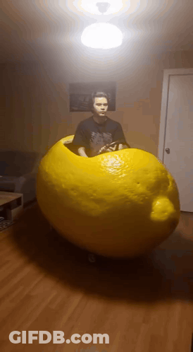 Man In Black Shirt Standing Next To Giant Lemon GIF