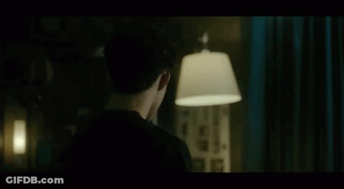 Man In Black Shirt Standing With Lamp In Dark Room GIF