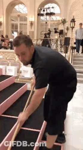 Man In Black Shirt Sweeping Floor GIF